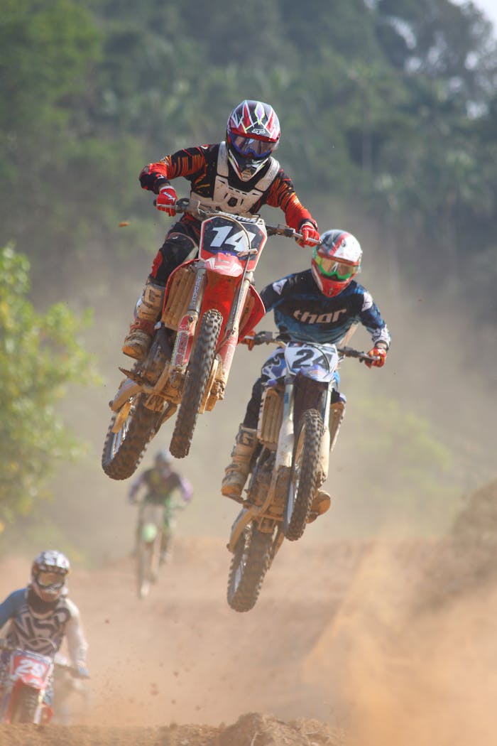 Offerings Exciting motocross race with bikers performing jumps on a dusty trail outdoors.