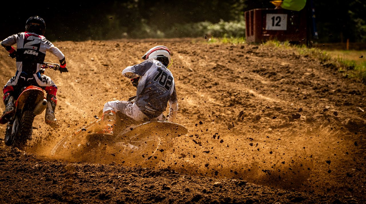 Home Exciting motocross action scene on a sunlit dirt track capturing the speed and agility of riders.