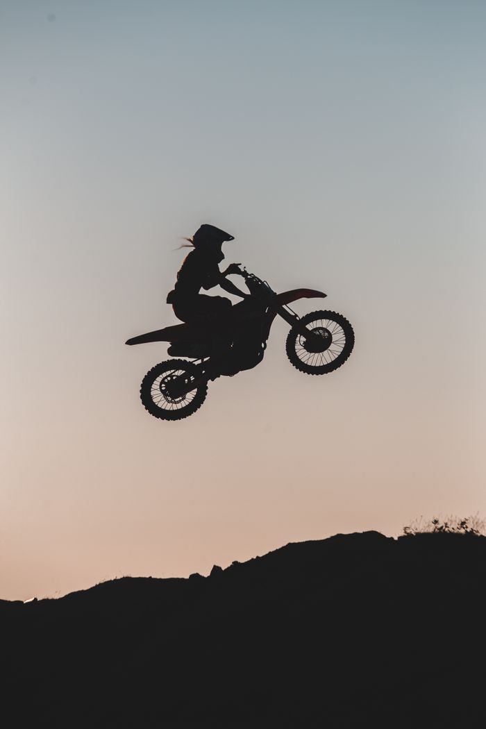 Offerings Dynamic motocross silhouette of a rider mid-air against a vibrant sunset sky.
